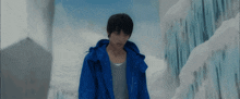 a man in a blue jacket is standing in front of a snowy wall