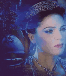 a woman wearing a tiara and a necklace is looking at the camera