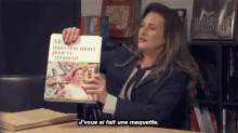 a woman holding a book that says j'vous ai fait une maquette on it