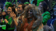 a group of women in green clothes are clapping