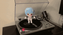 a doll is standing on top of a turntable that says audio on it