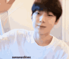a young man in a white t-shirt is waving his hand .