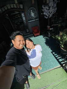a man and a woman are posing for a picture in front of a kabesara cafe