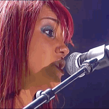 a woman singing into a microphone with red hair