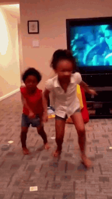 two little girls are jumping in the air in front of a television