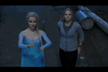 a woman in a blue dress is standing next to a woman in a gray cardigan .
