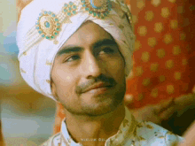 a man wearing a turban is smiling and looking at the camera .