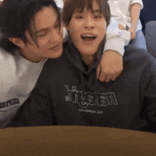 a man wearing a hoodie that says " hipster " is hugging another man