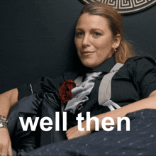 a woman in a suit and tie is sitting in a chair with the words well then behind her