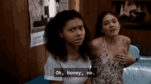 two women are sitting next to each other and one of them is holding her chest .