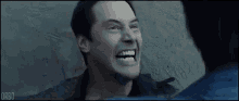 a man is laughing while standing next to another man in a bathroom .