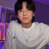 a young man with a piercing in his lip is wearing a white t-shirt and a necklace