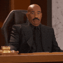 a bald man with a mustache is sitting at a desk in a courtroom