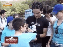 a man wearing a black t-shirt that says " collina " is talking to a young boy