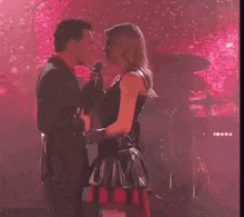 a man and a woman are dancing on a stage in front of a drum set .
