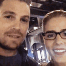 a man and a woman are posing for a picture together and the woman is wearing glasses