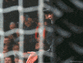 a blurred image of a man behind a fence with the caption millythegoat