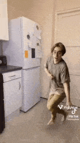 a young man is standing in front of a refrigerator in a kitchen .