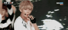 a man is singing into a microphone while holding a lollipop .