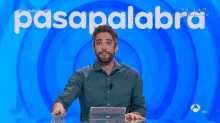 a man covering his face in front of a blue background with the word pasapalabra