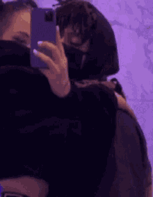 a man is taking a picture of himself in a mirror while hugging another man .