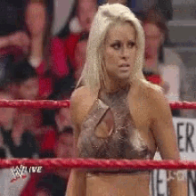 a woman is standing in a wrestling ring with the word alive on the bottom