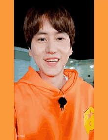 a young man wearing an orange hoodie with a yellow star on it