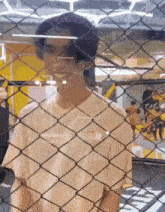 a young man is standing behind a chain link fence .