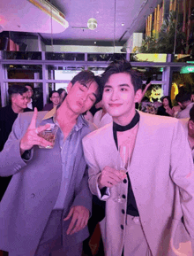a man in a suit holds a glass of beer next to another man
