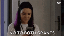 a woman with purple hair is holding a cell phone and says `` no to both grants '' .
