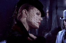 a woman wearing a veil and a hat looks down