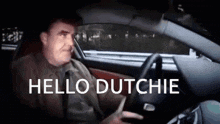 a man is driving a car with the words `` hello dutchie '' written on it .