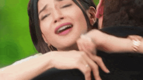 a man is hugging a woman who is crying and making a funny face .