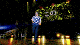 a man wearing glasses and a plaid vest is standing on a stage .