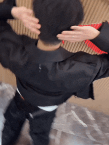 a man in a black jacket is dancing with his hands on his head