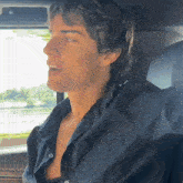 a man in a black shirt is sitting in a car with his arm outstretched