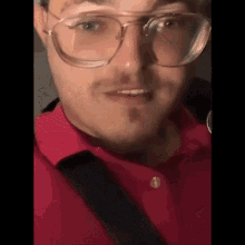 a man wearing glasses and a red shirt has a beard