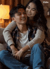 a man and a woman are sitting on a couch and the woman is hugging him