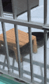 a wooden table behind a metal fence with a shadow on it