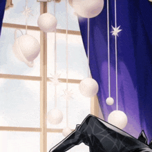 a window with a blue curtain and white balls hanging from the ceiling