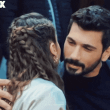 a man with a beard and braided hair kisses a woman