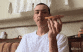 a man in a white shirt is eating a piece of toast with a vidu al logo in the background