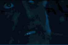 a close up of a man 's face in the dark with a beard and glowing eyes .