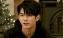 a young man wearing a black hoodie is looking at the camera