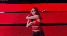 a woman with red hair is dancing on a stage in front of a red background .