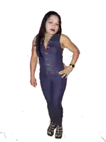a woman wearing a denim jumpsuit and heels stands with her hands on her hips
