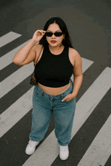 a woman wearing sunglasses is crossing a street