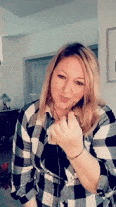 a woman wearing a black and white plaid shirt is making a face