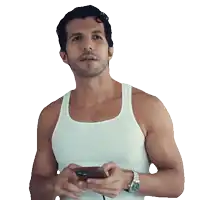 a man in a white tank top is holding a cellphone