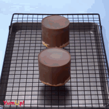 two chocolate covered cakes are sitting on a cooling rack with yumup written on the bottom right